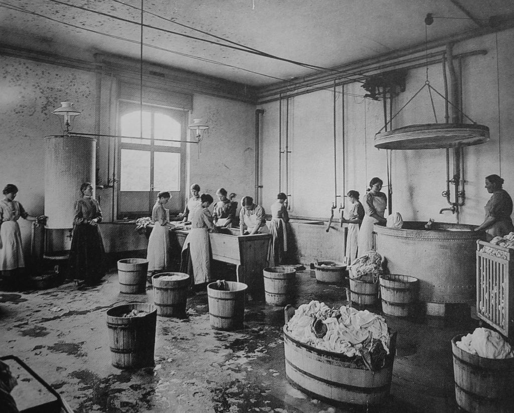 Mädchen mit Trögen voll Tücher und Kleidung in der Waschküche im Magdalenenheim Zürich